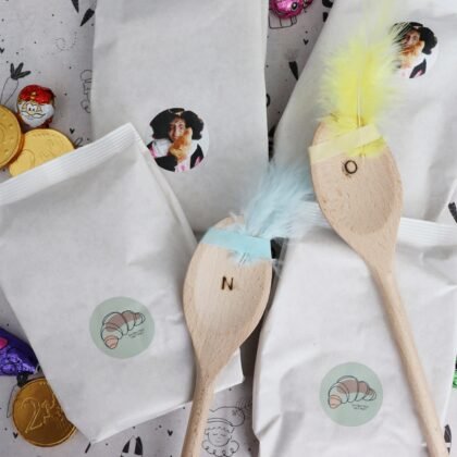 Kruidnotenbox met bakmixen en pollepels met washi tape en een veertje zodat het op een Piet lijkt