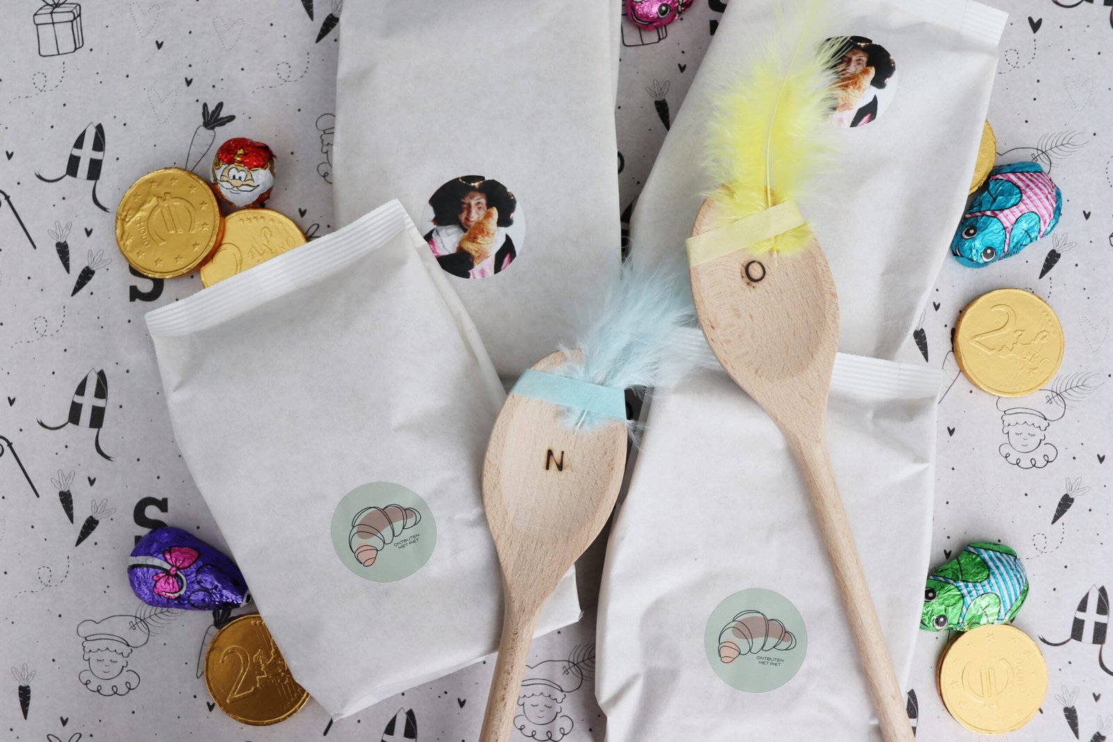 Kruidnotenbox met bakmixen en pollepels met washi tape en een veertje zodat het op een Piet lijkt